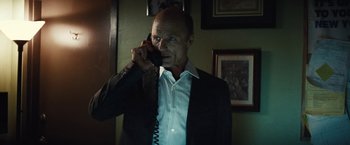 Movie still from “Run All Night” (2015), directed by Jaume Collet-Serra – A man in a suit and tie talking on a phone; Close Up shot, Low angle