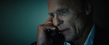 Movie still from “Run All Night” (2015), directed by Jaume Collet-Serra – An older man is holding his head down while talking on the phone; Close Up shot, Low angle