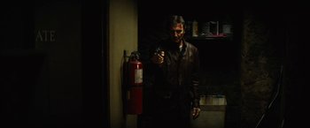 Movie still from “Run All Night” (2015), directed by Jaume Collet-Serra – A man holding a camera in front of a fire hydrant; Medium shot, Low angle