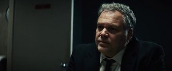 Movie still from “Run All Night” (2015), directed by Jaume Collet-Serra – A person wearing a suit and tie; Close Up shot, Over the shoulder angle