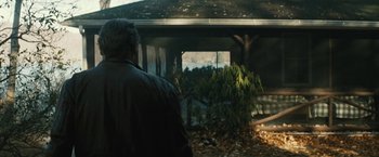 Movie still from “Run All Night” (2015), directed by Jaume Collet-Serra – A man standing in front of a house with leaves on the ground; Wide shot, Over the shoulder angle