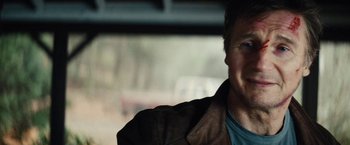Movie still from “Run All Night” (2015), directed by Jaume Collet-Serra – A person sitting in a car; Close Up shot, Over the shoulder angle