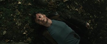 Movie still from “Run All Night” (2015), directed by Jaume Collet-Serra – A man laying on the ground in the grass; Medium shot, Overhead angle