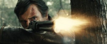 Movie still from “Run All Night” (2015), directed by Jaume Collet-Serra – A man is holding a gun and aiming at something; Close Up shot, Low angle