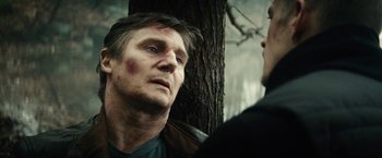 Movie still from “Run All Night” (2015), directed by Jaume Collet-Serra – A man looking at another man in a forest; Close Up shot, Low angle