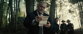 Movie still from “Run All Night” (2015), directed by Jaume Collet-Serra – A man in a suit and tie looking at a piece of paper; Close Up shot, Low angle