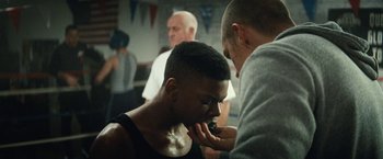 Movie still from “Run All Night” (2015), directed by Jaume Collet-Serra – A man with a shaved head is getting his face shaved by another man; Close Up shot, Over the shoulder angle