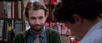 Movie still from “Notting Hill” (1999), directed by Roger Michell – A man with a beard and a tie in a store; Close Up shot, Over the shoulder angle