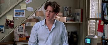 Movie still from “Notting Hill” (1999), directed by Roger Michell – A man in a blue dress shirt is standing in a room; Close Up shot, Low angle