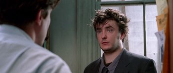 Movie still from “Notting Hill” (1999), directed by Roger Michell – A man in a suit and tie looking at himself in the mirror; Close Up shot, Over the shoulder angle