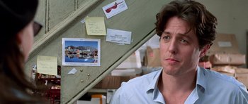 Movie still from “Notting Hill” (1999), directed by Roger Michell – A man standing in front of a wall covered in notes; Close Up shot, Over the shoulder angle