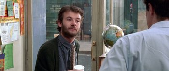 Movie still from “Notting Hill” (1999), directed by Roger Michell – A man with a beard is holding a cup of coffee; Close Up shot, Over the shoulder angle