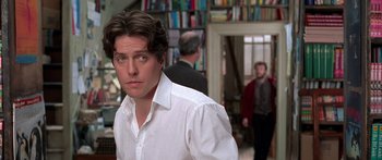 Movie still from “Notting Hill” (1999), directed by Roger Michell – A man standing in front of some people; Close Up shot, Over the shoulder angle