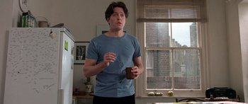 Movie still from “Notting Hill” (1999), directed by Roger Michell – A man standing in a kitchen holding a cup; Medium shot, Low angle