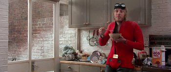 Movie still from “Notting Hill” (1999), directed by Roger Michell – A man holding a bowl of food in a cluttered kitchen; Medium shot, Low angle