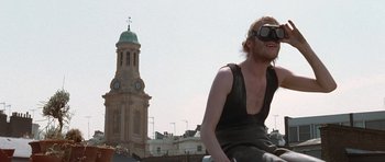 Movie still from “Notting Hill” (1999), directed by Roger Michell – A man riding a bike in front of a clock tower; Medium shot, Low angle