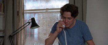 Movie still from “Notting Hill” (1999), directed by Roger Michell – A man talking on a phone while sitting at a desk; Medium shot, Low angle