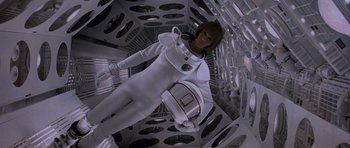 Movie still from “Notting Hill” (1999), directed by Roger Michell – A woman in a spacesuit is standing in a room; Medium shot, Overhead angle