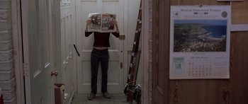 Movie still from “Notting Hill” (1999), directed by Roger Michell – A person standing in front of a door holding up a newspaper; Medium shot, Overhead angle