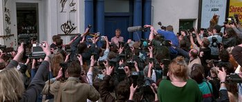 Movie still from “Notting Hill” (1999), directed by Roger Michell – A crowd of people gathered around a man in front of a building; Wide shot, High angle