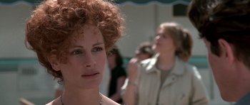 Movie still from “Notting Hill” (1999), directed by Roger Michell – A woman with curly red hair is looking at the camera; Close Up shot, Over the shoulder angle