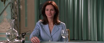Movie still from “Notting Hill” (1999), directed by Roger Michell – A woman sitting at a table with a glass of wine in front of her; Medium shot, Over the shoulder angle
