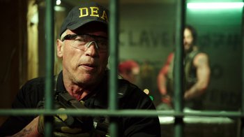 Movie still from “Sabotage” (2014), directed by David Ayer – A man wearing a hat sitting behind bars; Close Up shot, Low angle