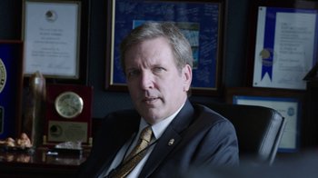 Movie still from “Sabotage” (2014), directed by David Ayer – A person wearing a suit and tie; Close Up shot, Over the shoulder angle