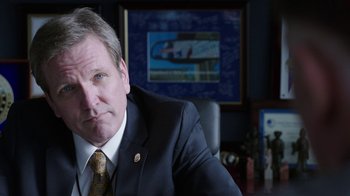 Movie still from “Sabotage” (2014), directed by David Ayer – A person wearing a suit and tie; Close Up shot, Over the shoulder angle