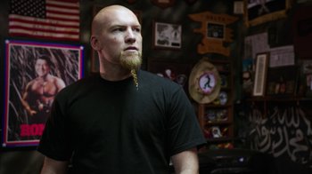 Movie still from “Sabotage” (2014), directed by David Ayer – A bald man with a long beard is standing in front of a wall; Close Up shot, Low angle