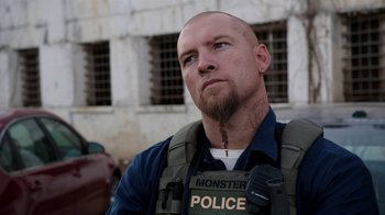 Movie still from “Sabotage” (2014), directed by David Ayer – A man with a shaved head wearing a police uniform; Close Up shot, Over the shoulder angle