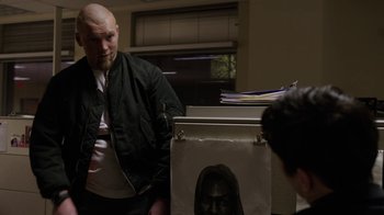 Movie still from “Sabotage” (2014), directed by David Ayer – A man standing in front of a drawing of a face; Medium shot, Over the shoulder angle