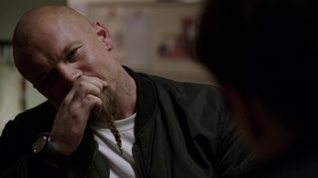 Movie still from “Sabotage” (2014), directed by David Ayer – A man with a beard and a mustache is sitting down; Close Up shot, Over the shoulder angle