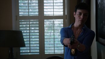 Movie still from “Sabotage” (2014), directed by David Ayer – A woman holding a remote control in her hand; Medium shot, Over the shoulder angle