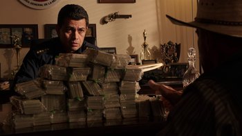 Movie still from “Sabotage” (2014), directed by David Ayer – A man sitting in front of a pile of money; Medium shot, Low angle