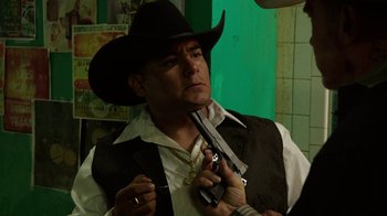 Movie still from “Sabotage” (2014), directed by David Ayer – A man in a cowboy hat holding a gun; Medium shot, Over the shoulder angle