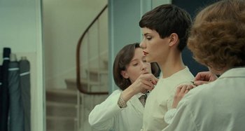 Movie still from “Saint Laurent” (2014), directed by Bertrand Bonello – A young woman is helping a young man put on a tie; Medium shot, Over the shoulder angle