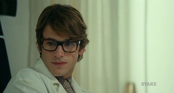 Movie still from “Saint Laurent” (2014), directed by Bertrand Bonello – A man in a lab coat and tie; Close Up shot, Over the shoulder angle