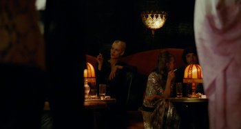 Movie still from “Saint Laurent” (2014), directed by Bertrand Bonello – Two women sitting at a table in a restaurant; Medium shot, Over the shoulder angle