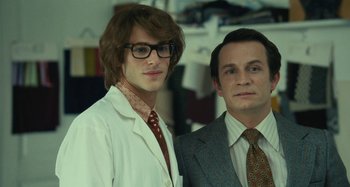 Movie still from “Saint Laurent” (2014), directed by Bertrand Bonello – Two men in suits and ties posing for a picture; Close Up shot, Low angle