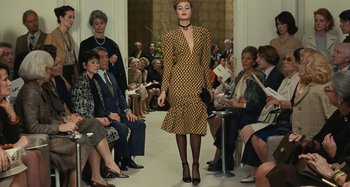 Movie still from “Saint Laurent” (2014), directed by Bertrand Bonello – A woman is walking down the runway in a dress; Wide shot, Low angle