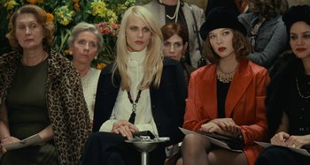 Movie still from “Saint Laurent” (2014), directed by Bertrand Bonello – A group of women sitting next to each other in a room; Medium shot, Over the shoulder angle