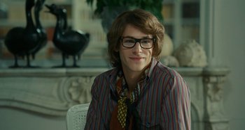 Movie still from “Saint Laurent” (2014), directed by Bertrand Bonello – A young man wearing a striped shirt and a tie; Close Up shot, Over the shoulder angle