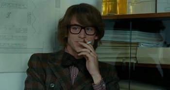 Movie still from “Saint Laurent” (2014), directed by Bertrand Bonello – A young man smoking a cigarette while wearing a bow tie; Close Up shot, Over the shoulder angle