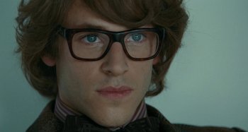 Movie still from “Saint Laurent” (2014), directed by Bertrand Bonello – A person wearing glasses and a suit; Close Up shot, Over the shoulder angle