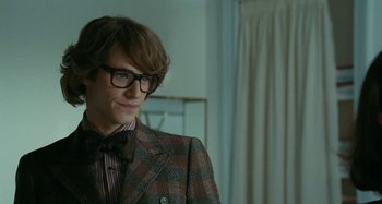 Movie still from “Saint Laurent” (2014), directed by Bertrand Bonello – A young man in a suit and bow tie; Close Up shot, Over the shoulder angle