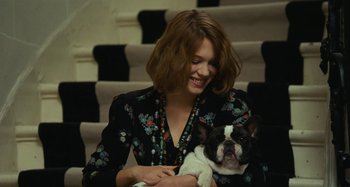 Movie still from “Saint Laurent” (2014), directed by Bertrand Bonello – A woman holding a dog in her arms; Medium shot, High angle