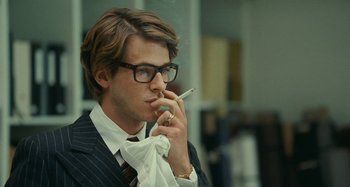 Movie still from “Saint Laurent” (2014), directed by Bertrand Bonello – A man smoking a cigarette while wearing a suit; Close Up shot, Over the shoulder angle