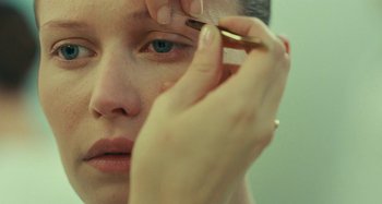 Movie still from “Saint Laurent” (2014), directed by Bertrand Bonello – A woman is putting makeup on her eyes; Extreme Close Up shot, Over the shoulder angle