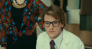 Movie still from “Saint Laurent” (2014), directed by Bertrand Bonello – A young man wearing a white lab coat and glasses; Close Up shot, Over the shoulder angle